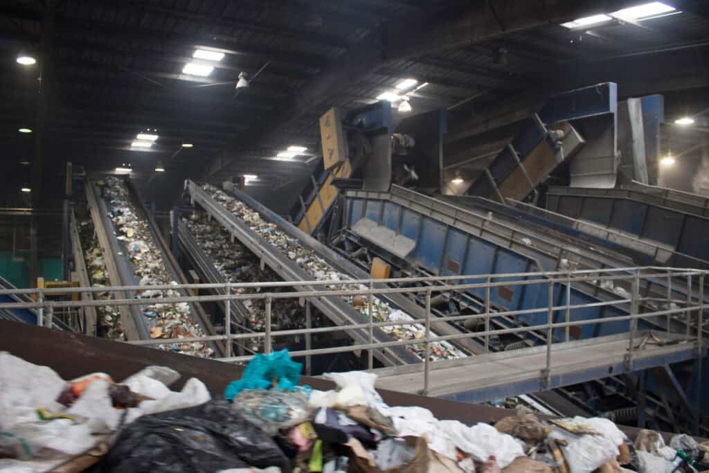 A photo of a MSW System. Waste is moving across multiple conveyor belts